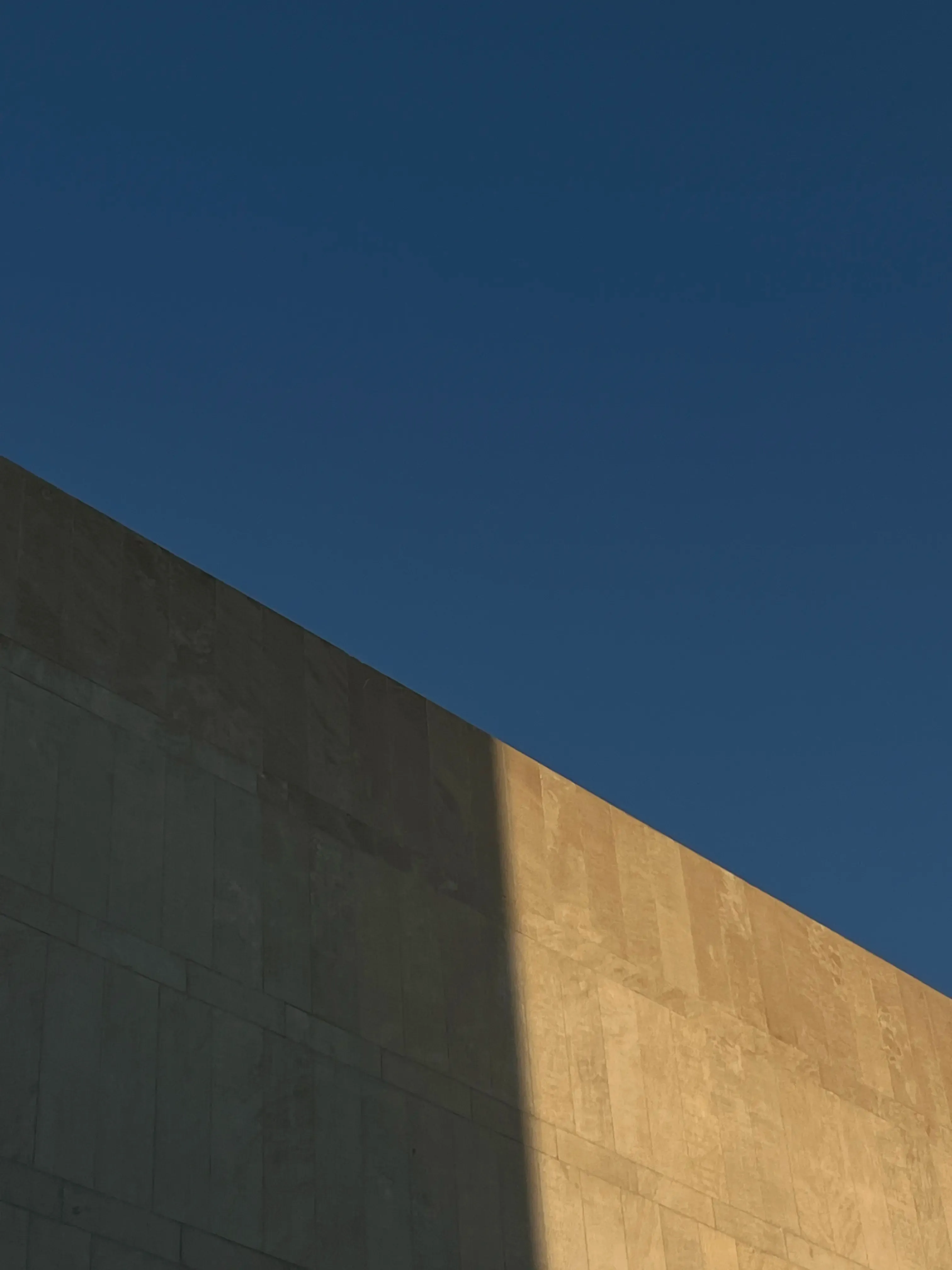 Blue sky with a brutalist structure in the bottom of the frame.