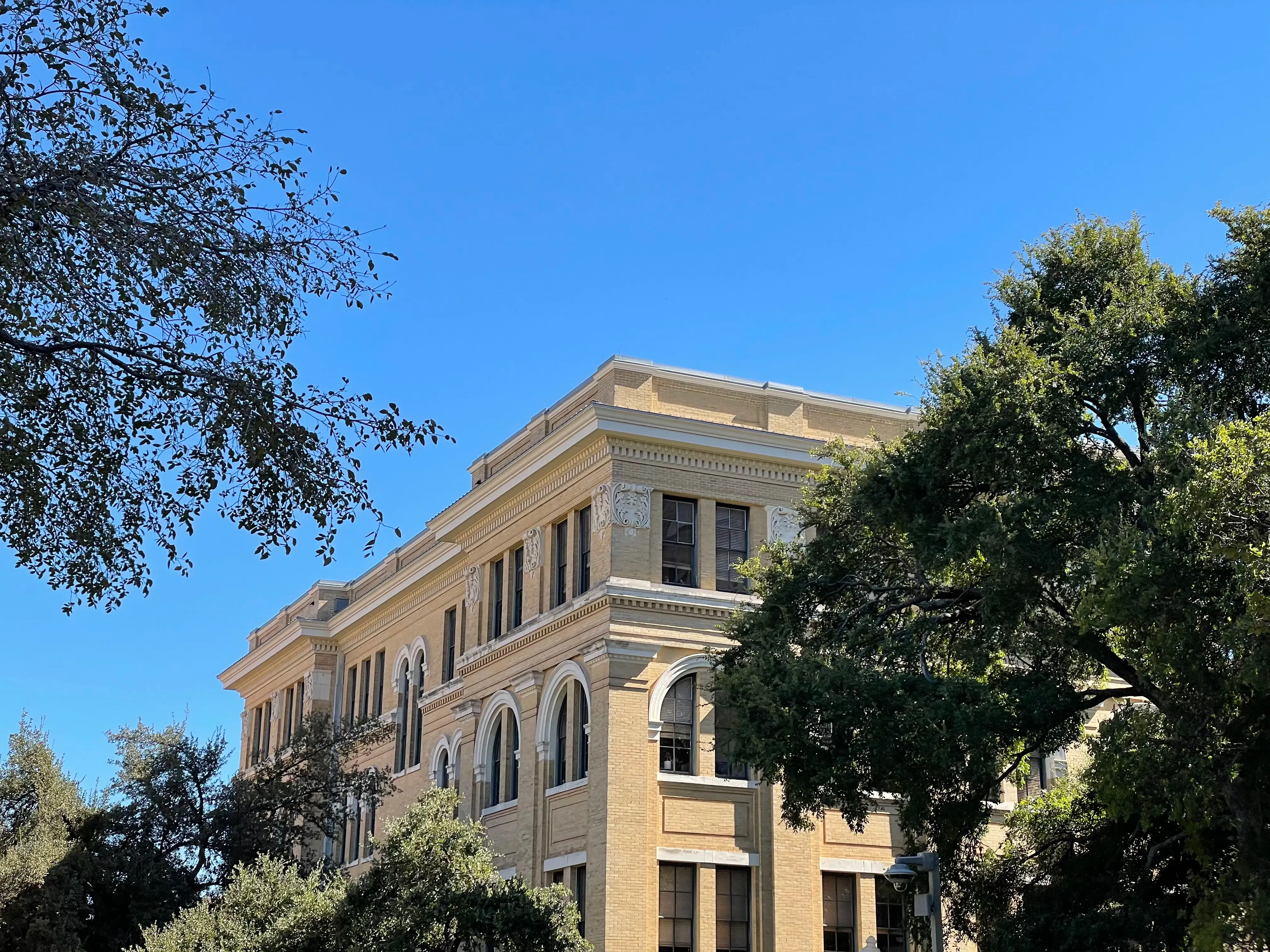 Blue sky with a building and trees in the bottom of the frame.